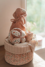 Load image into Gallery viewer, A soft baby toy in the shape of a ball with floral patterns and pink ribbed sections, featuring a label and a small rattle.