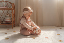 Load image into Gallery viewer, A soft baby toy in the shape of a ball with floral patterns and pink ribbed sections, featuring a label and a small rattle.