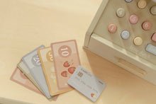 Load image into Gallery viewer, Set of colourful play money and a toy cash register on a beige surface