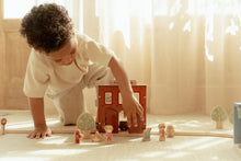 Load image into Gallery viewer, Child playing with wooden toy train set on a light-colored floor.