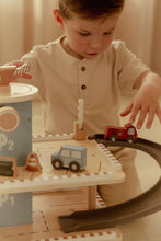 Load image into Gallery viewer, Child playing with a toy train set on a wooden table.