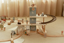 Load image into Gallery viewer, Wooden toy train set with tracks and buildings on a beige floor.