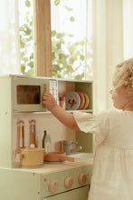 Load image into Gallery viewer, Child playing with a toy kitchen set in a bright room with large windows.