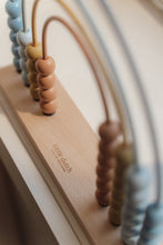 Load image into Gallery viewer, Close-up of a wooden toy with colourful beads and a rope, featuring the brand Little Dutch
