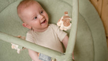 Load image into Gallery viewer, Baby in a green baby bouncer holding a plush toy
