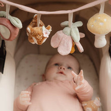 Load image into Gallery viewer, Baby with the stroller toy chain featuring plush toys including a mushroom, a deer, a flower, and a strawberry, attached to a pink strap.
