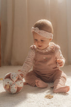 Load image into Gallery viewer, A soft baby toy in the shape of a ball with floral patterns and pink ribbed sections, featuring a label and a small rattle.
