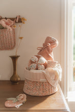 Load image into Gallery viewer, A soft baby toy in the shape of a ball with floral patterns and pink ribbed sections, featuring a label and a small rattle.
