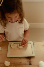 Load image into Gallery viewer, Child playing with heart-shaped cookies on a wooden table
