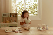 Load image into Gallery viewer, Child playing with kitchen toys at a table in a bright room with a window.
