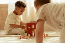Load image into Gallery viewer, Two children playing with wooden toys on a light-coloured floor.

