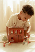Load image into Gallery viewer, Child playing with a toy fire station set on a light-coloured floor.
