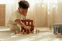 Load image into Gallery viewer, Child playing with toys on a light-coloured floor with soft lighting
