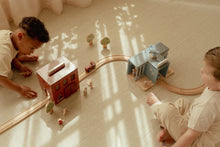 Load image into Gallery viewer, Two children playing with a wooden train set on a light-coloured floor.
