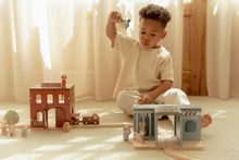 Load image into Gallery viewer, Child playing with toy train set on a light-coloured floor with curtains in the background

