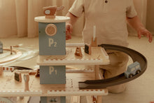 Load image into Gallery viewer, Child playing with a wooden toy train set on a light-coloured floor.
