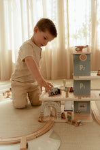 Load image into Gallery viewer, Child playing with a toy train set on a wooden floor 
