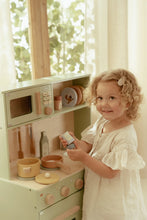 Load image into Gallery viewer, Child playing with a wooden toy kitchen set in a bright room.
