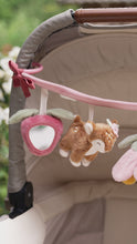 Load and play video in Gallery viewer, Cot with the stroller toy chain featuring plush toys including a mushroom, a deer, a flower, and a strawberry, attached to a pink strap.
